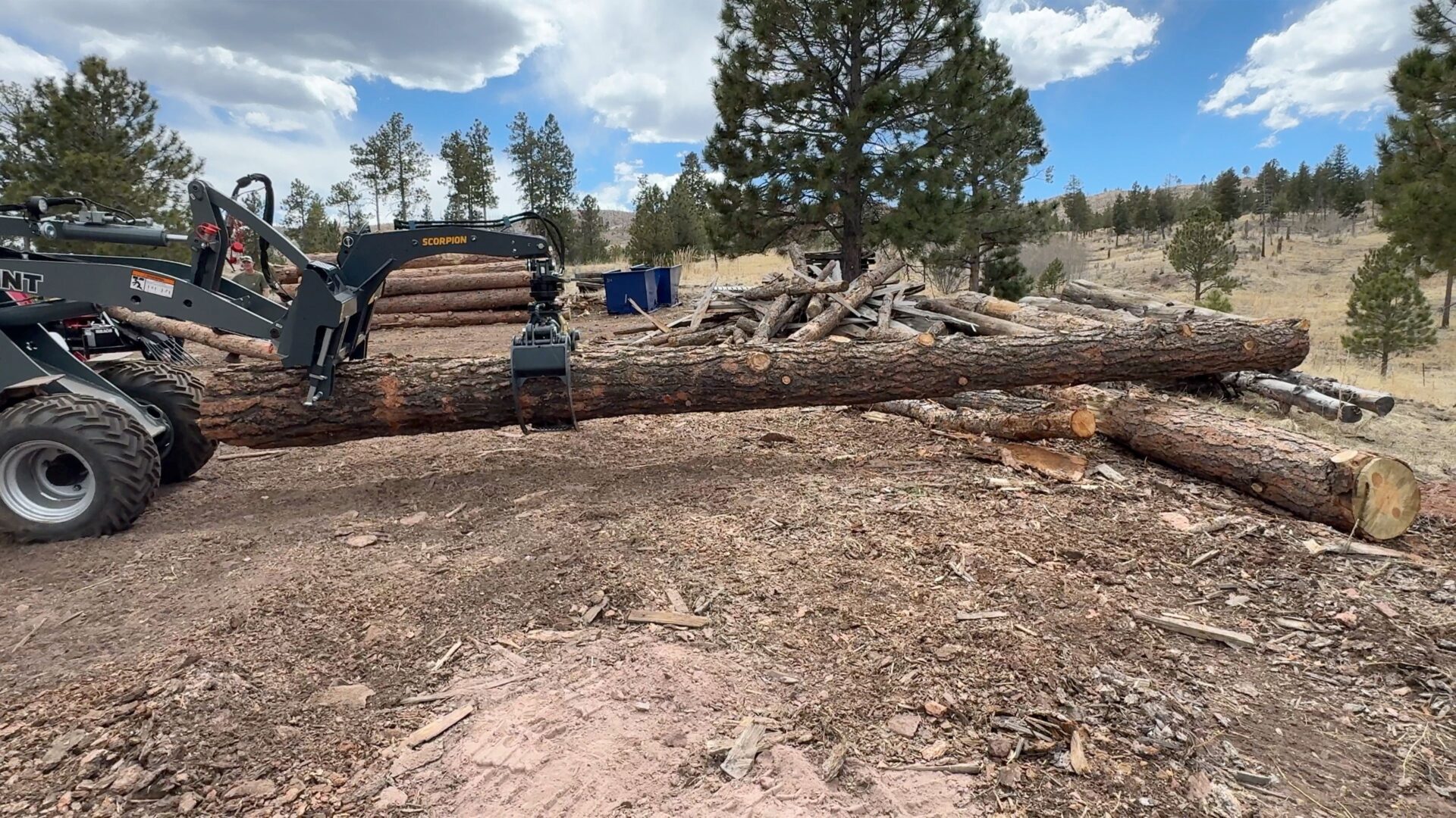 A large log is being cut down by a tractor.