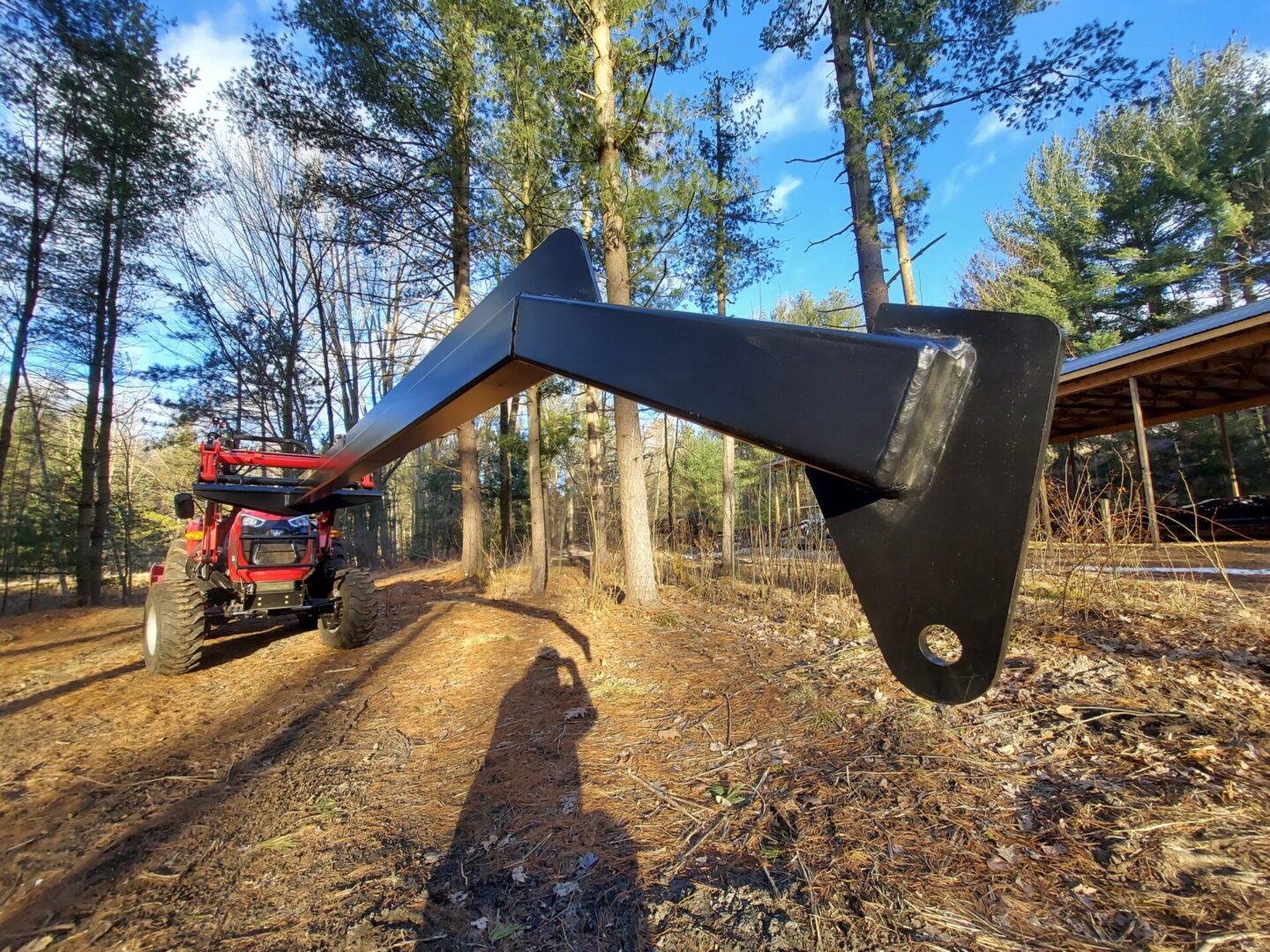 A tractor is parked in the woods near trees.