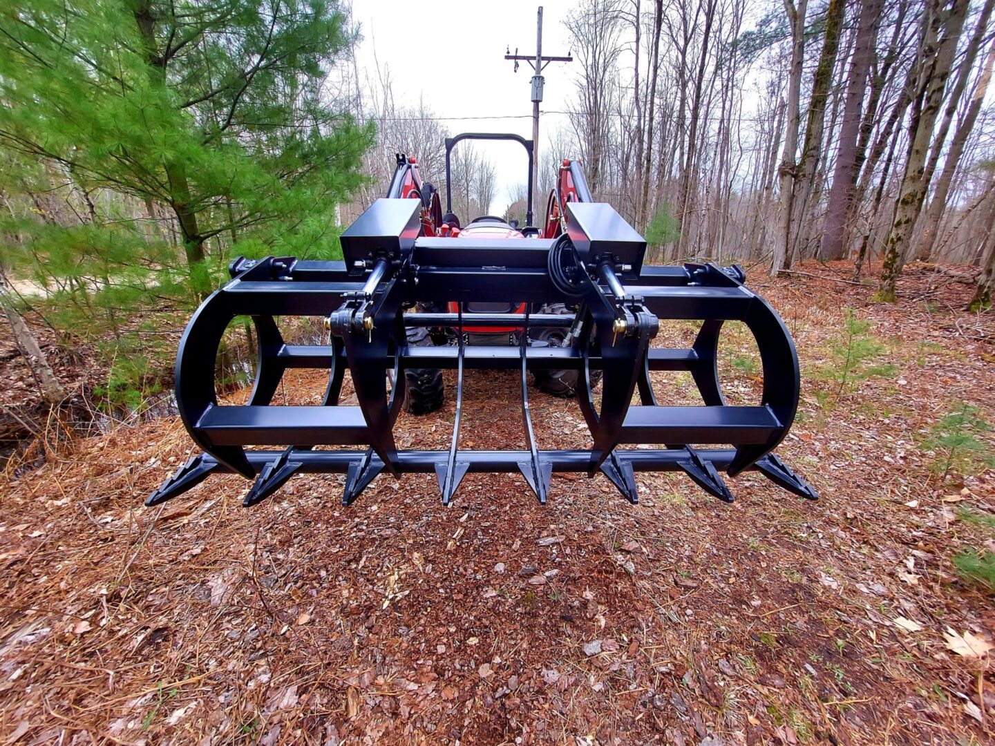 A tractor with a plow attachment in the middle of a forest.