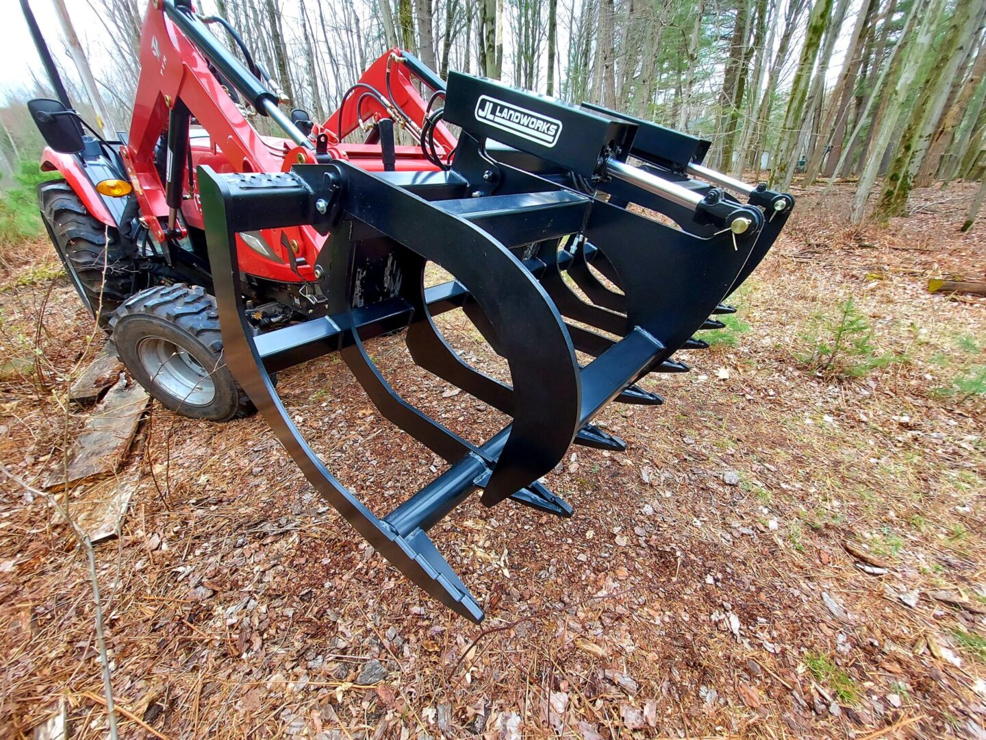 A red tractor with a black attachment on the back of it.