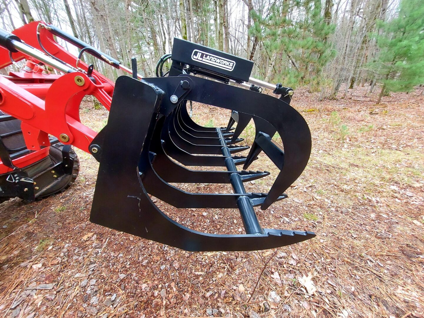 A red and black tractor with a large metal grapple.