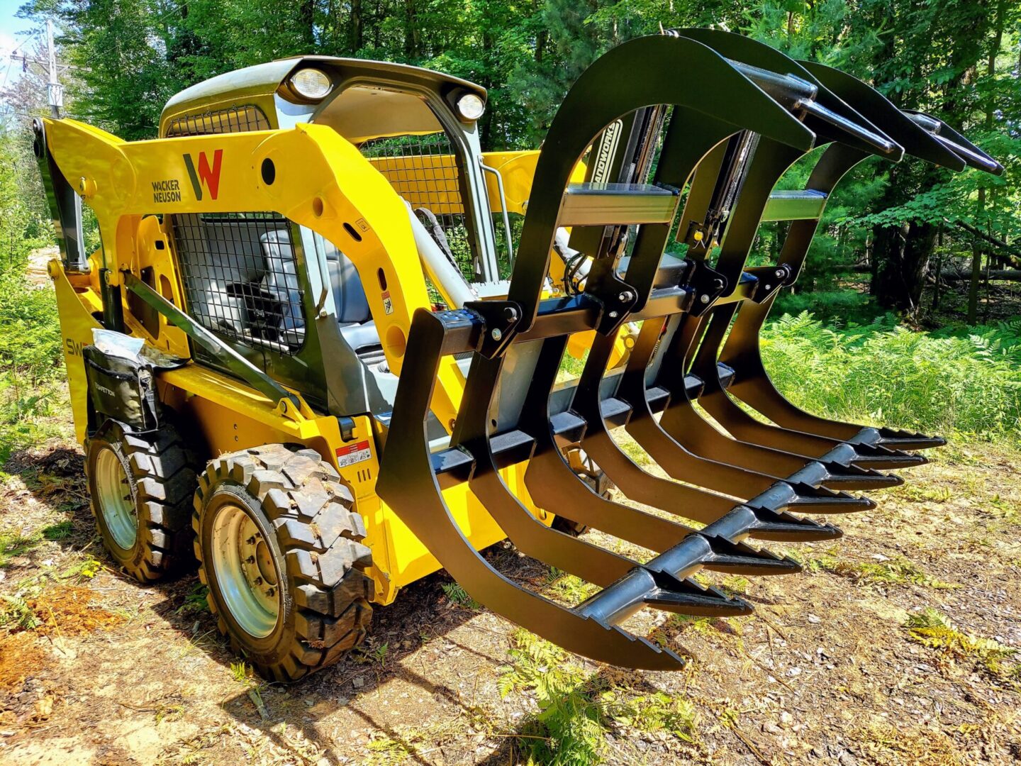 A yellow and black tractor with a large claw fork.