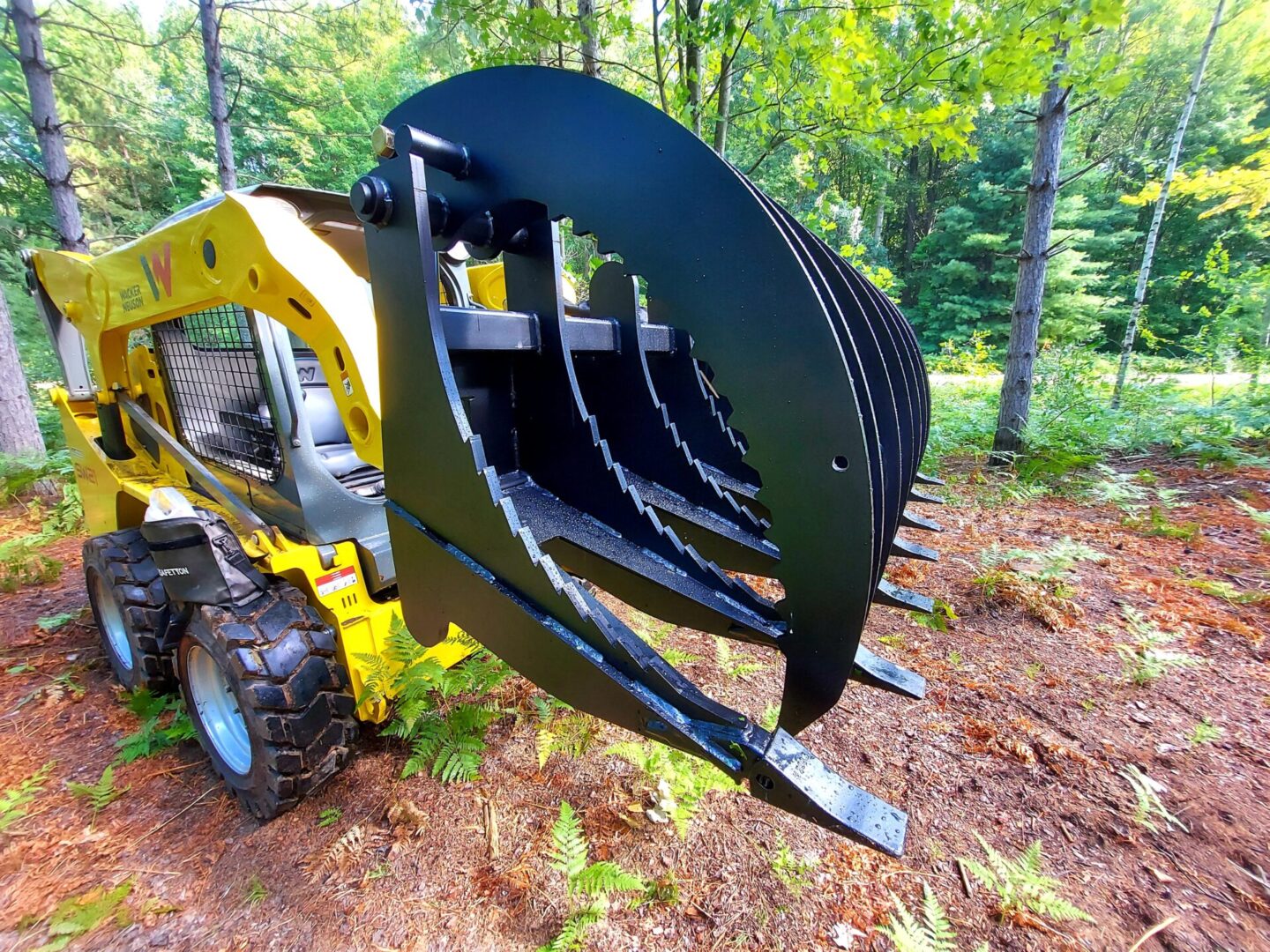 A yellow and black tractor with a large claw attachment.