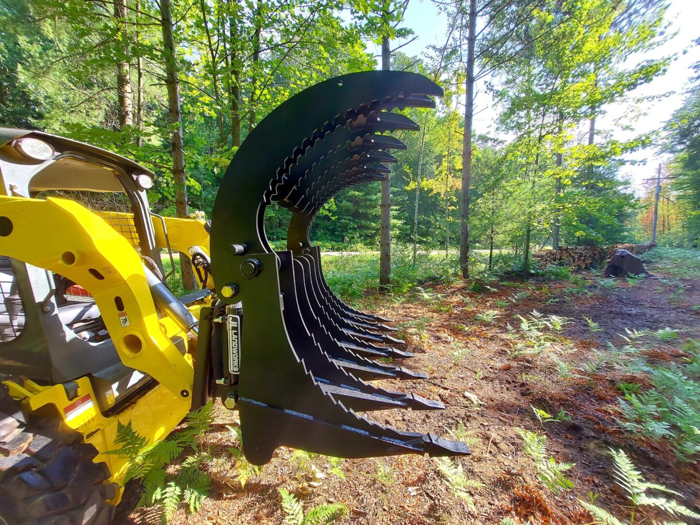 A yellow and black tractor with trees in the background