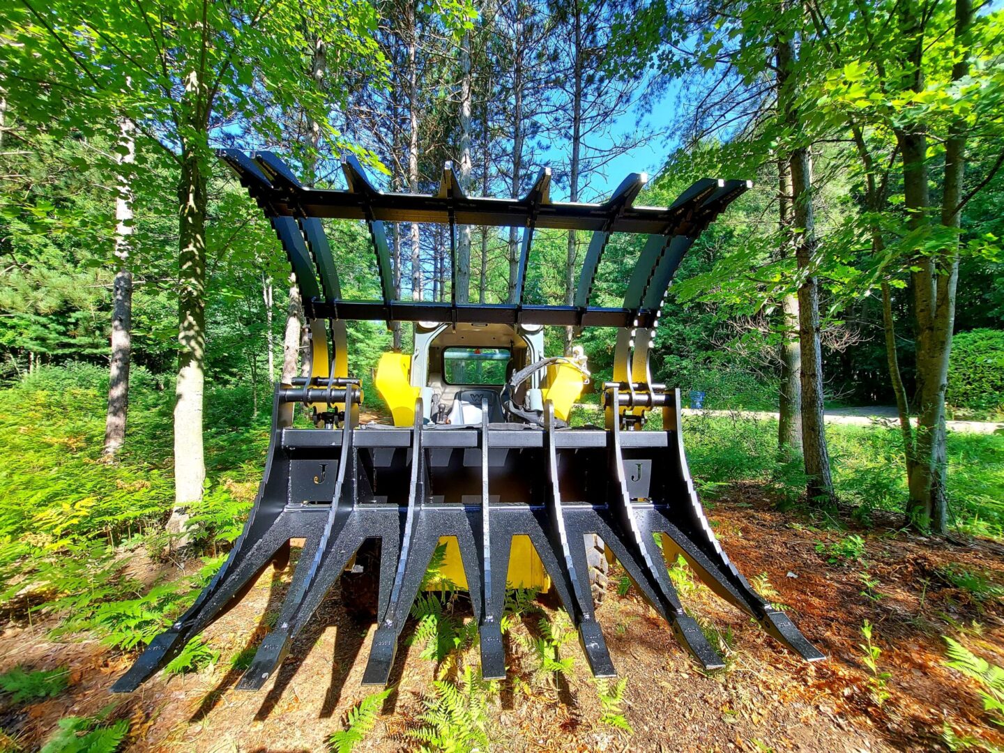 A large yellow and black machine in the middle of a forest.