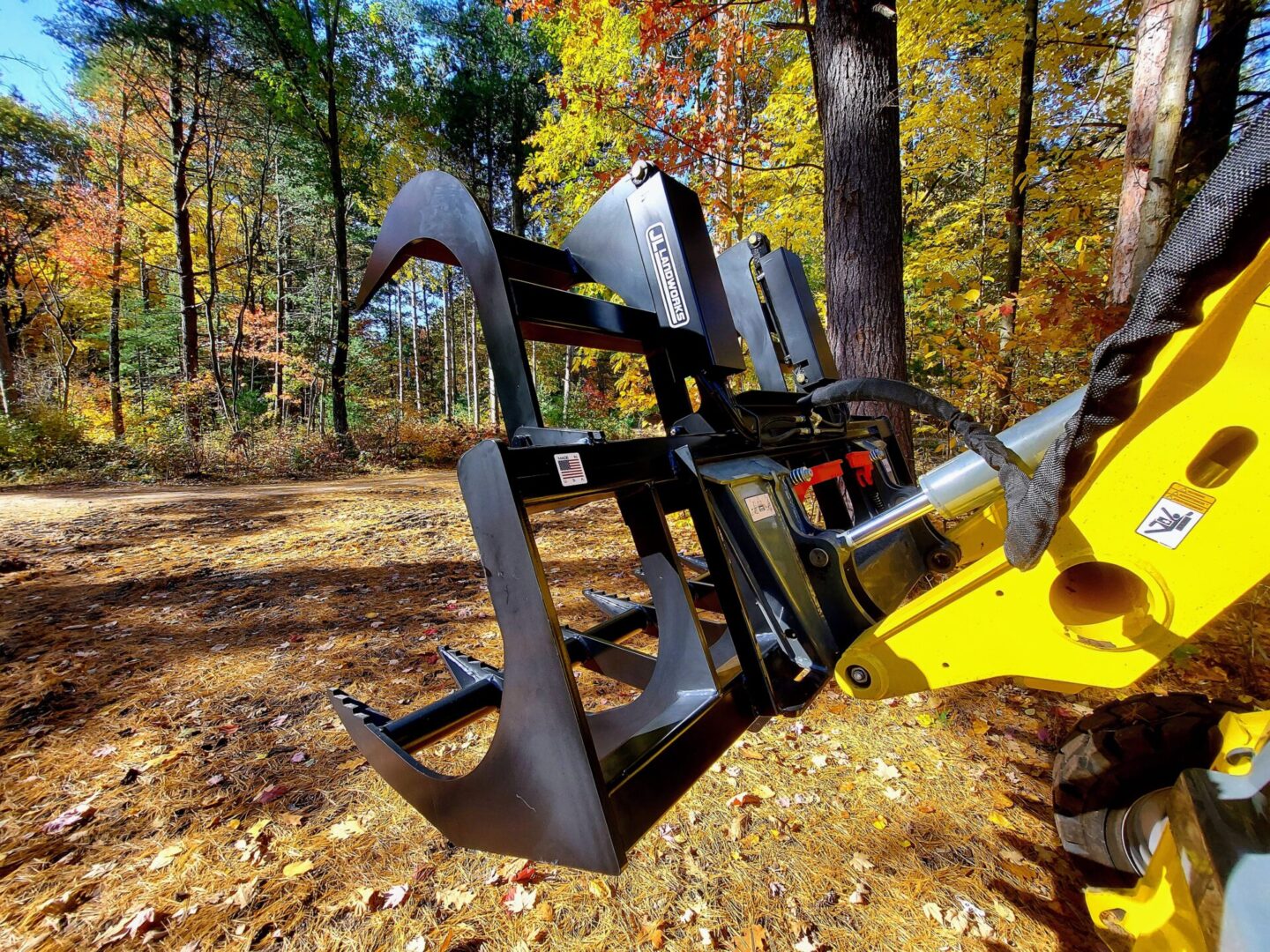 A yellow and black tractor with a tree in the background