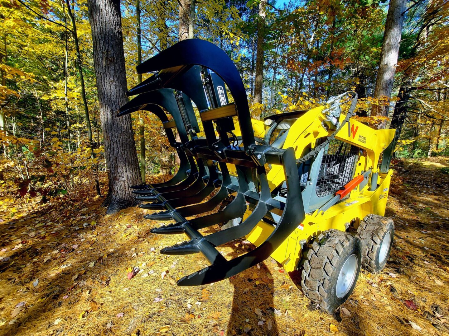 A yellow and black wheel loader is parked in the woods.