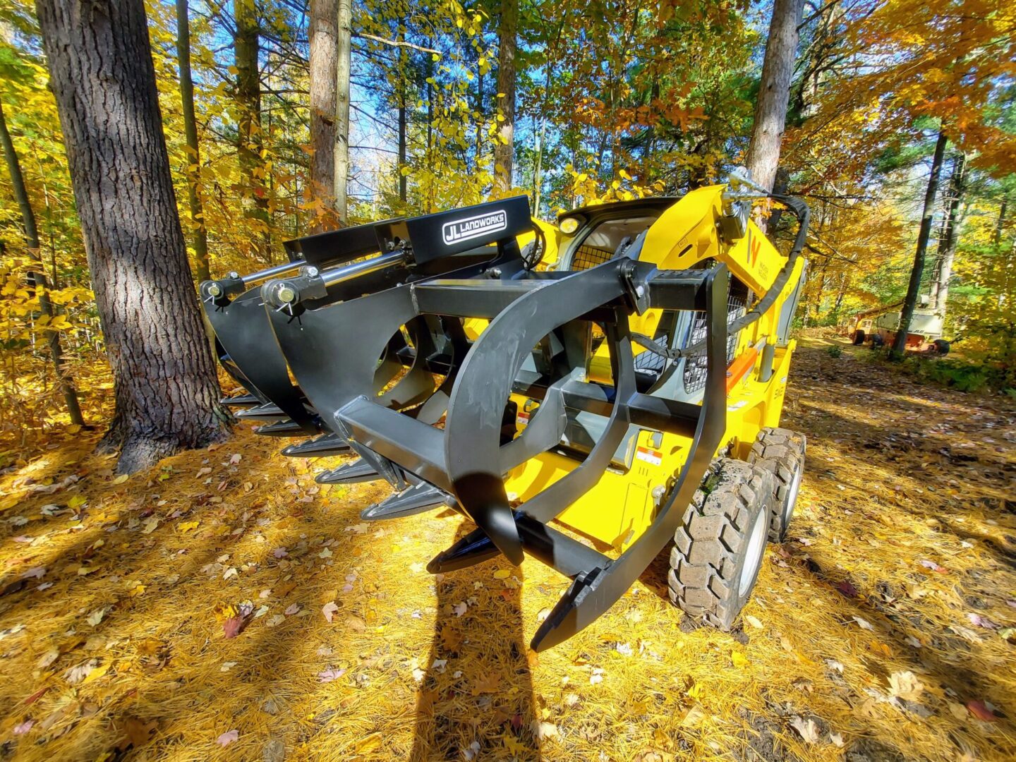 A yellow and black skid steer with a tree in the background.