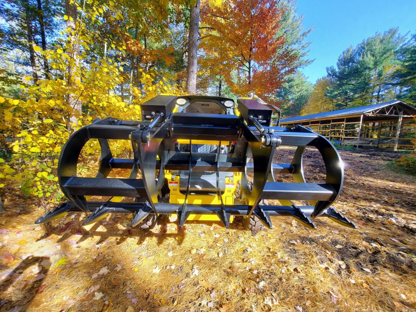 A black and yellow tractor with trees in the background