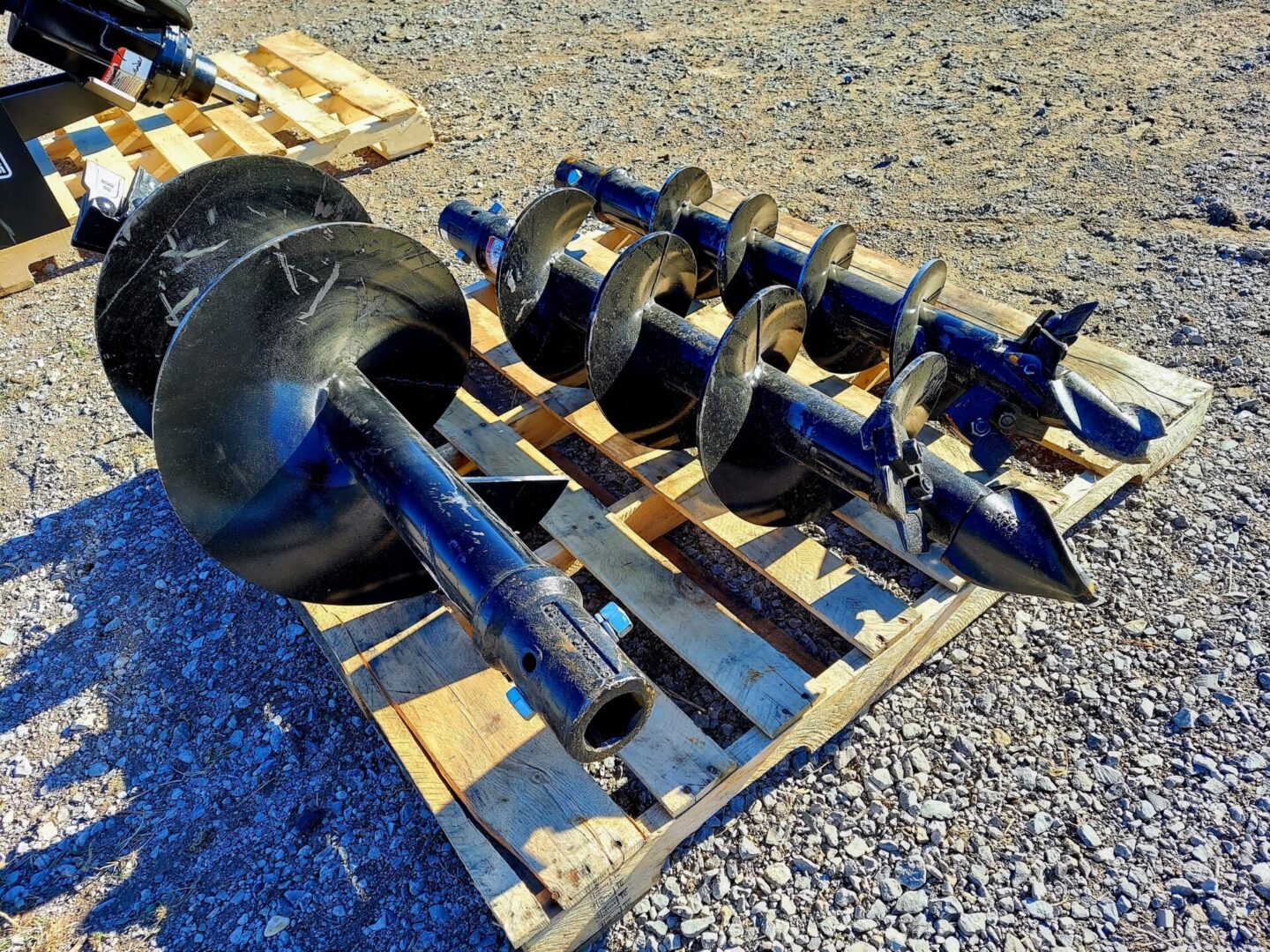 A pallet of various metal parts on top of gravel.