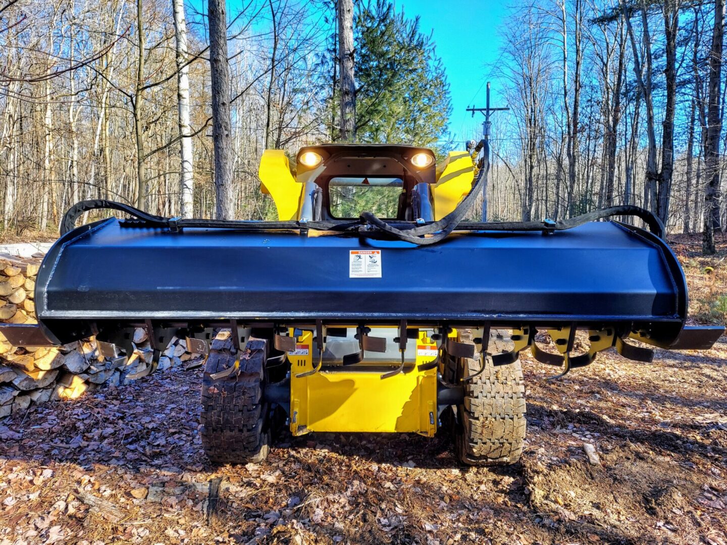 A yellow and black tractor is in the woods