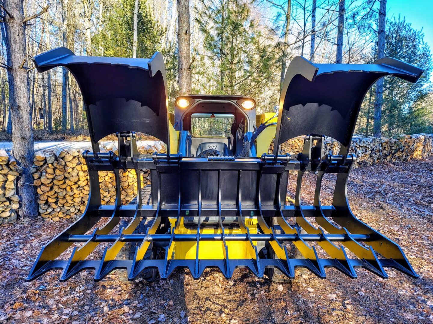 A yellow and black tractor with its back end in the woods.