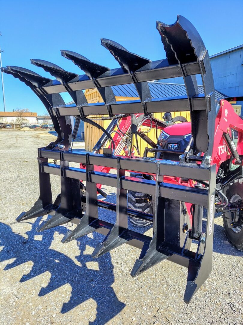 A tractor with four forks attached to it.