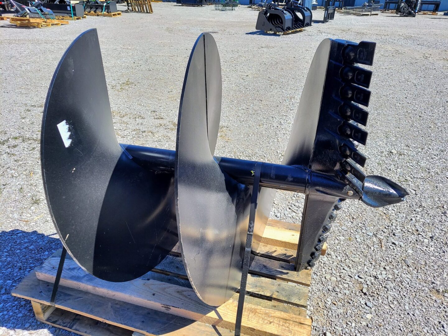 A black metal plow sitting on top of a wooden pallet.