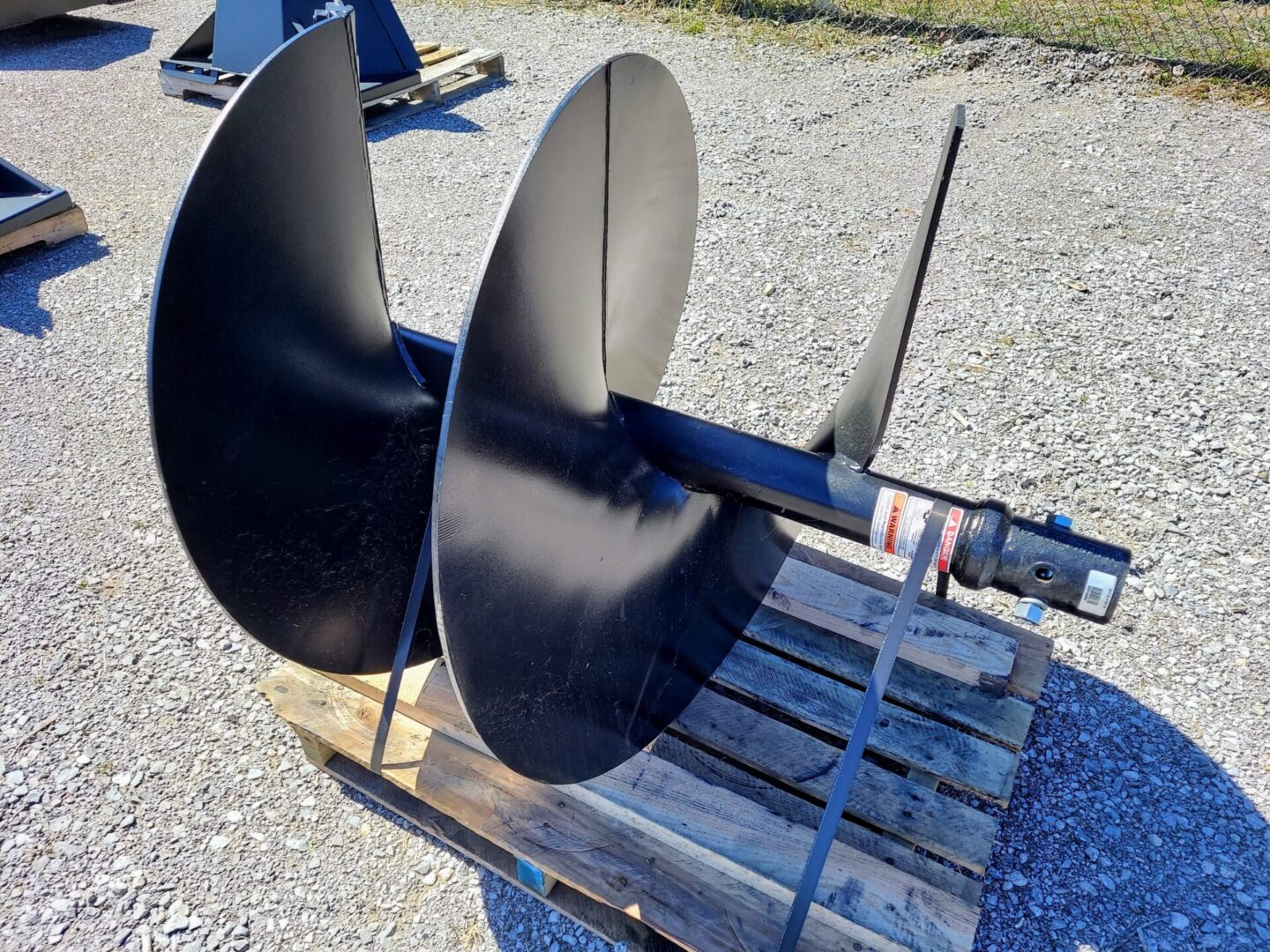 A black propeller sitting on top of a wooden pallet.