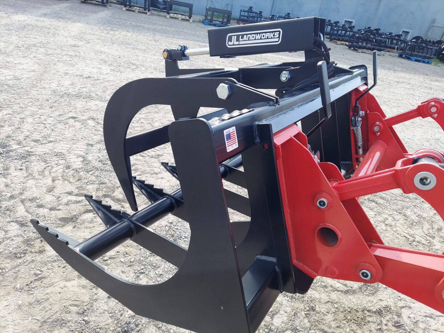 A red and black tractor attachment is sitting on the ground.