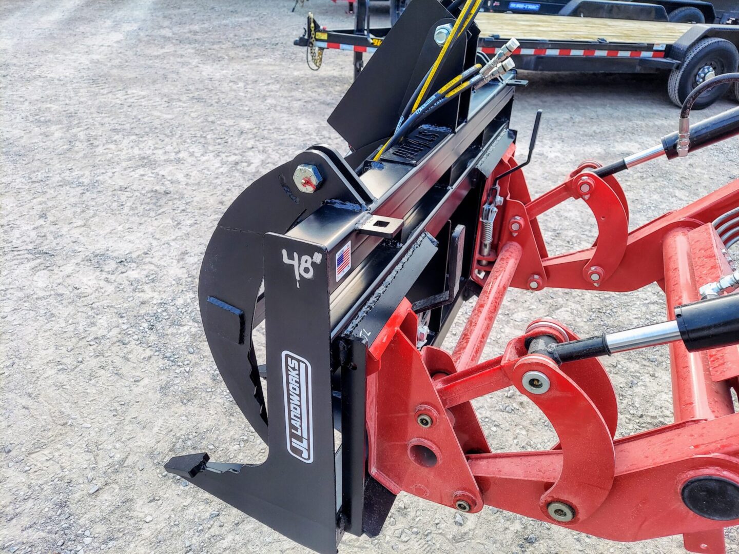 A red plow is attached to the back of a tractor.