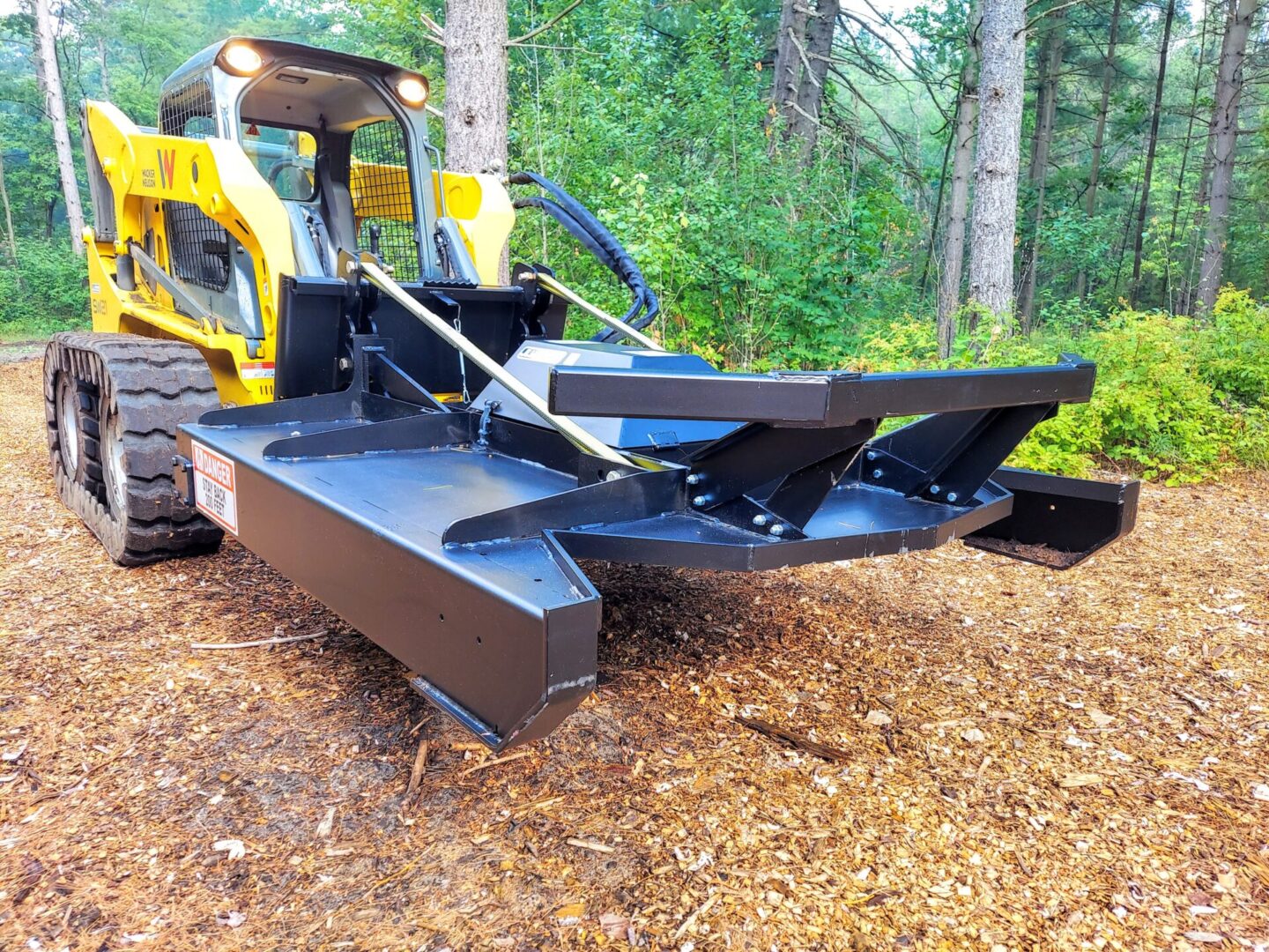 A yellow and black tractor is parked in the woods