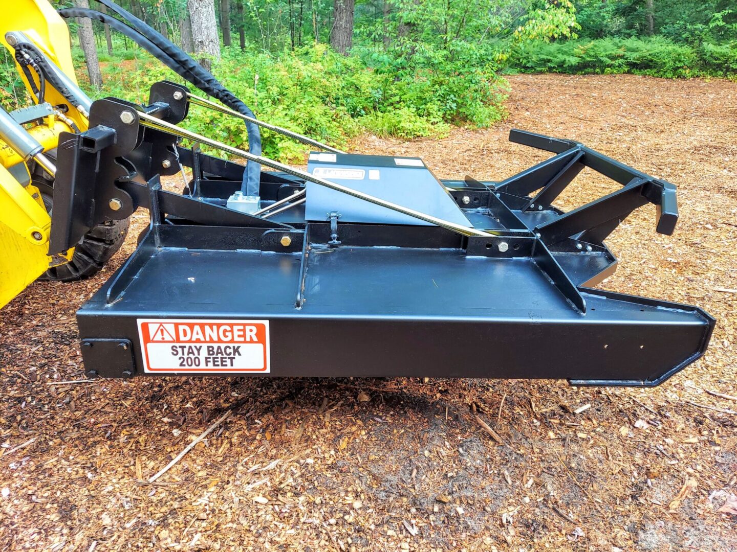 A black tractor with a red danger sign on it.