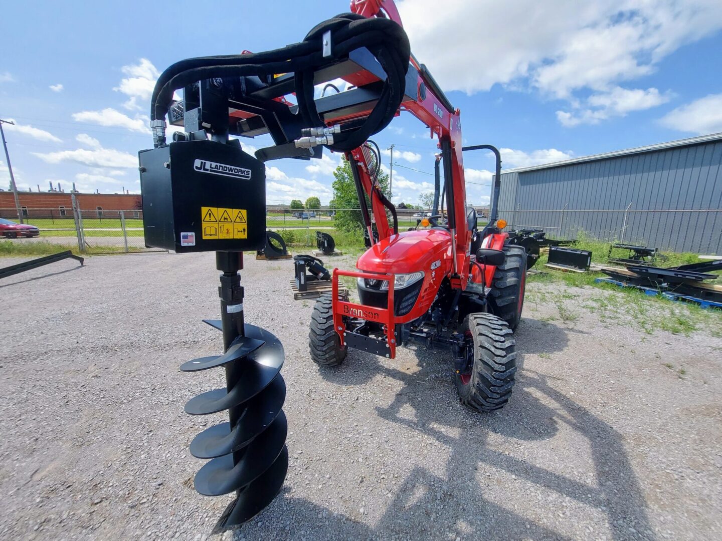 A tractor with a post hole digger attached to it.