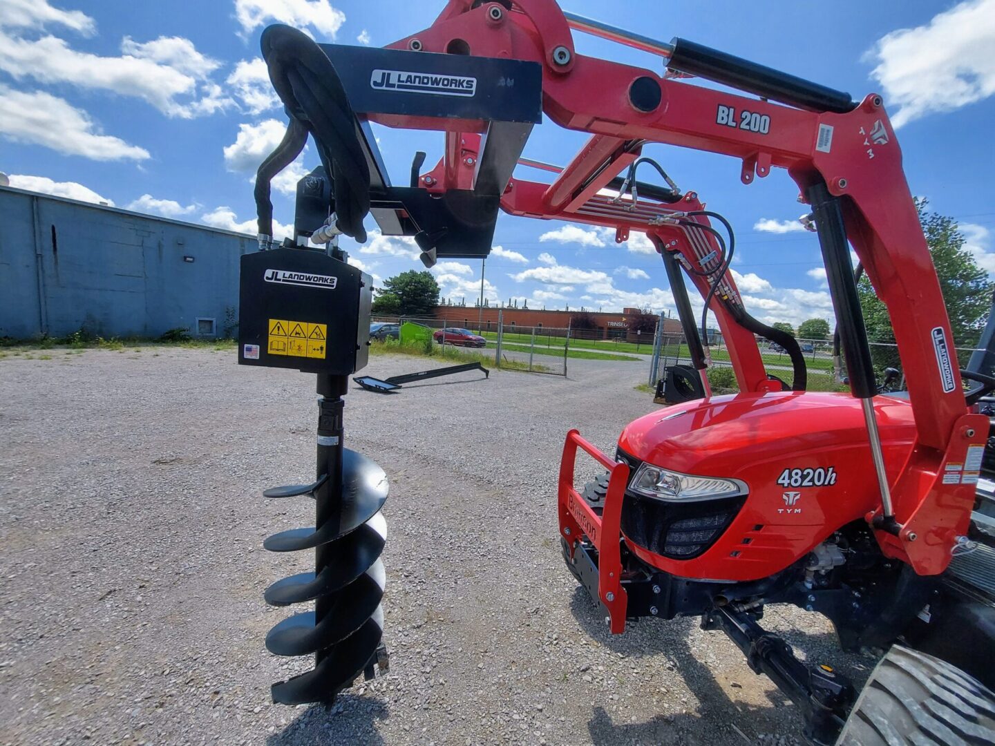 A red tractor with a black post hole digger.