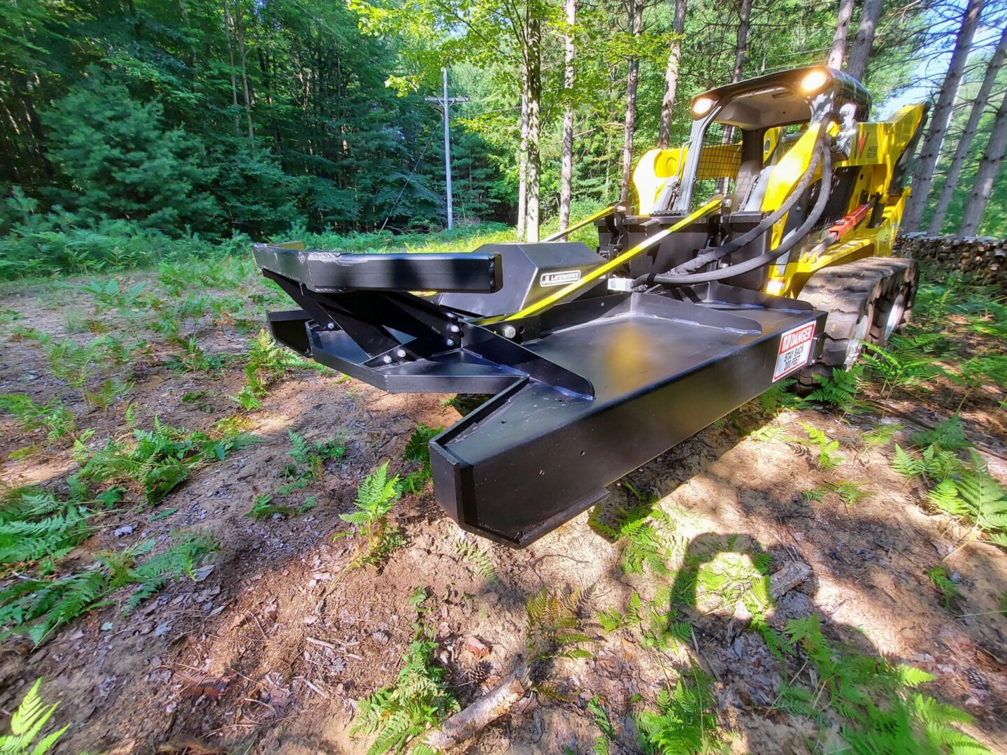 A yellow and black tractor is in the woods