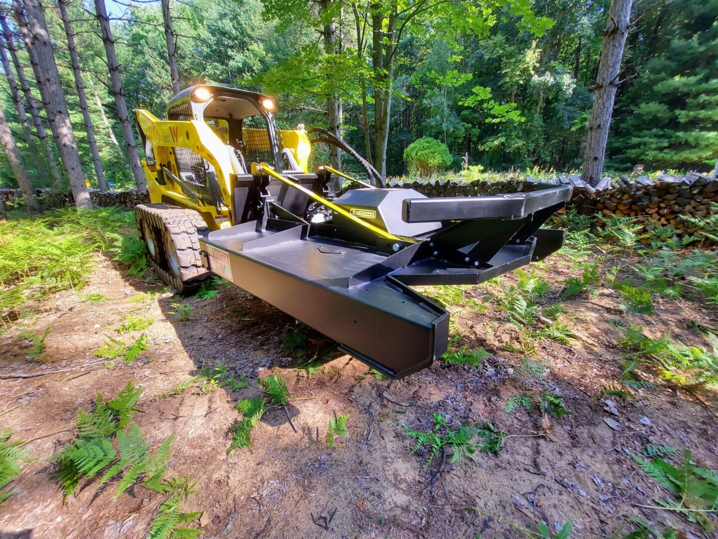 A yellow and black tractor is in the woods