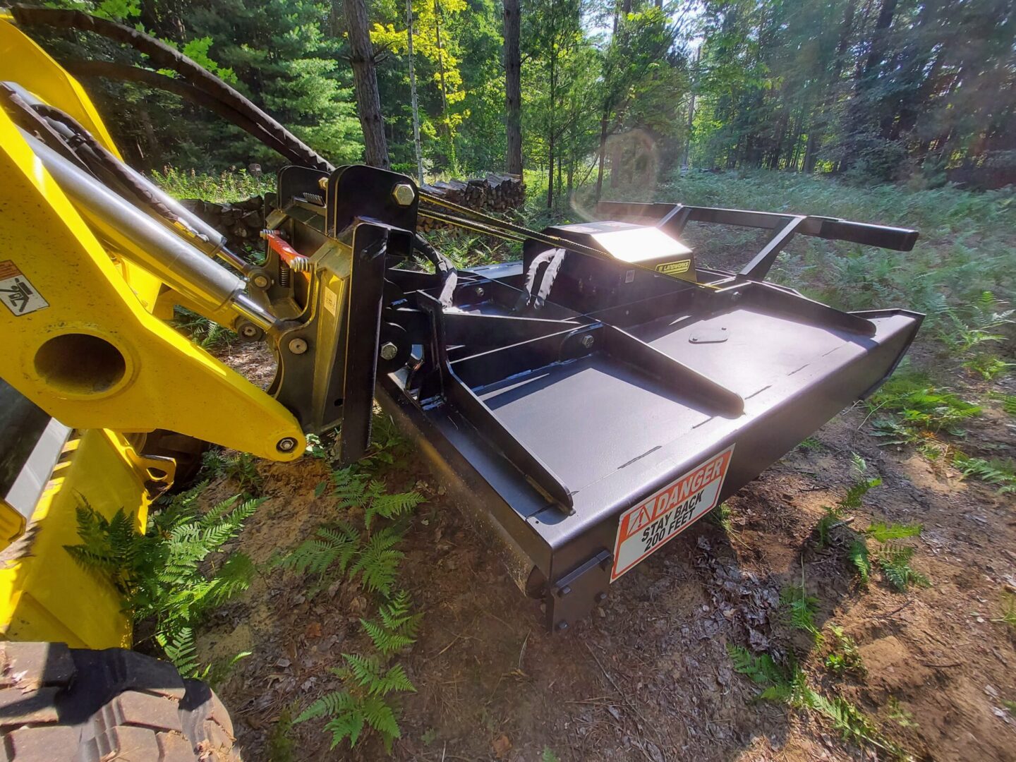 A yellow and black tractor is parked in the woods