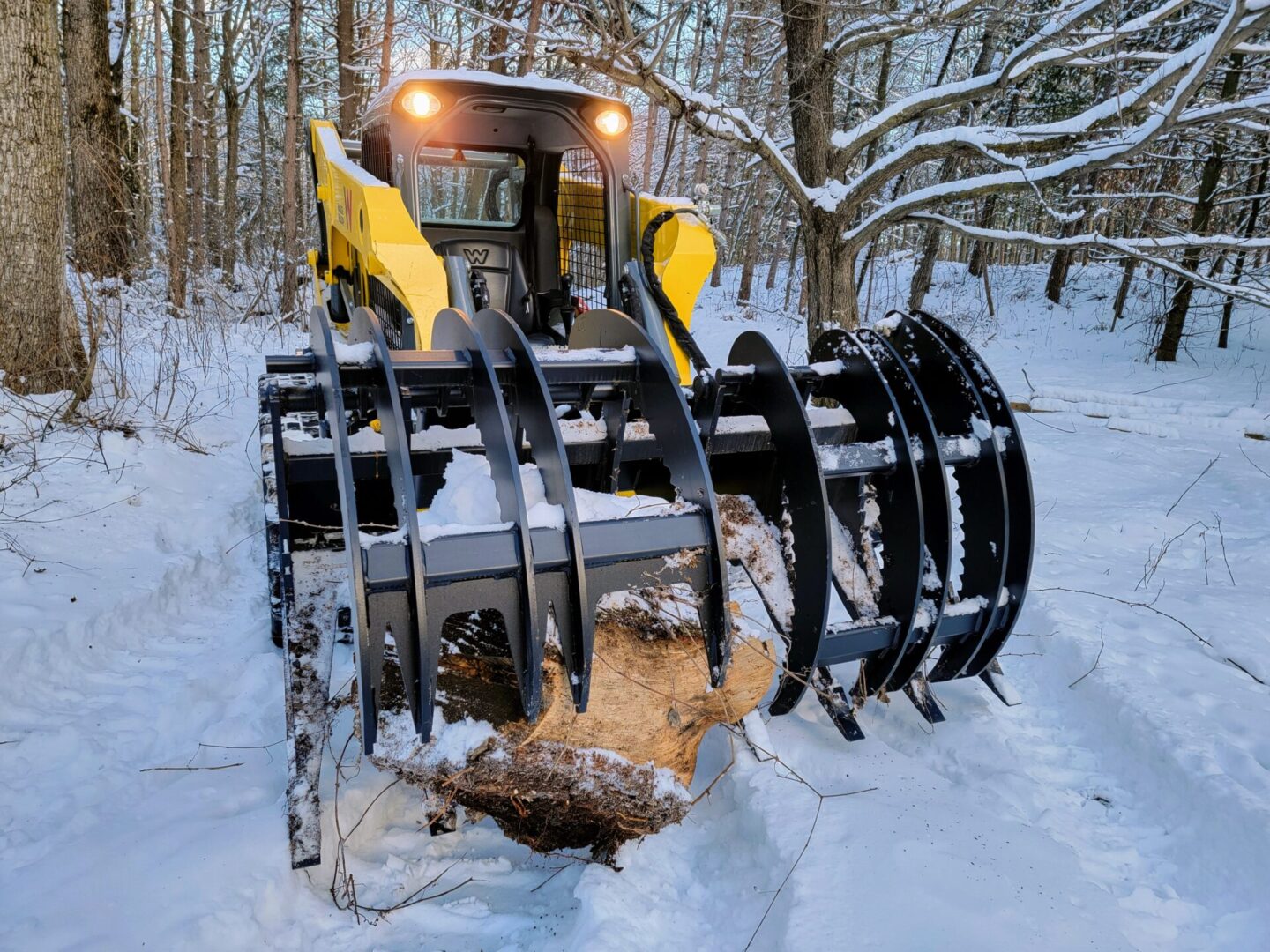 A tractor with a large wood grapple in the snow.