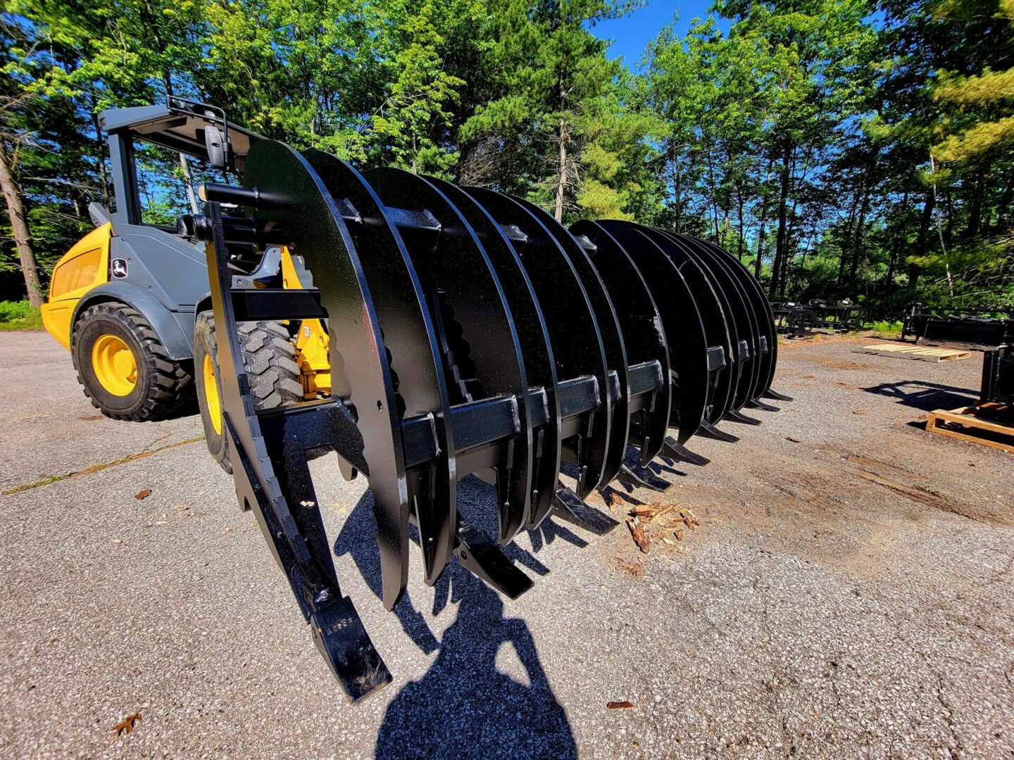 A large black metal plow sitting on top of gravel.