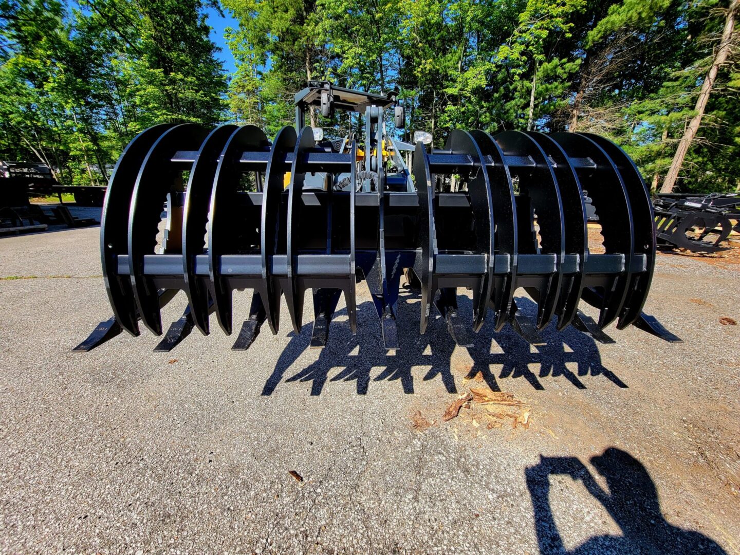 A large black metal plow sitting on top of a road.