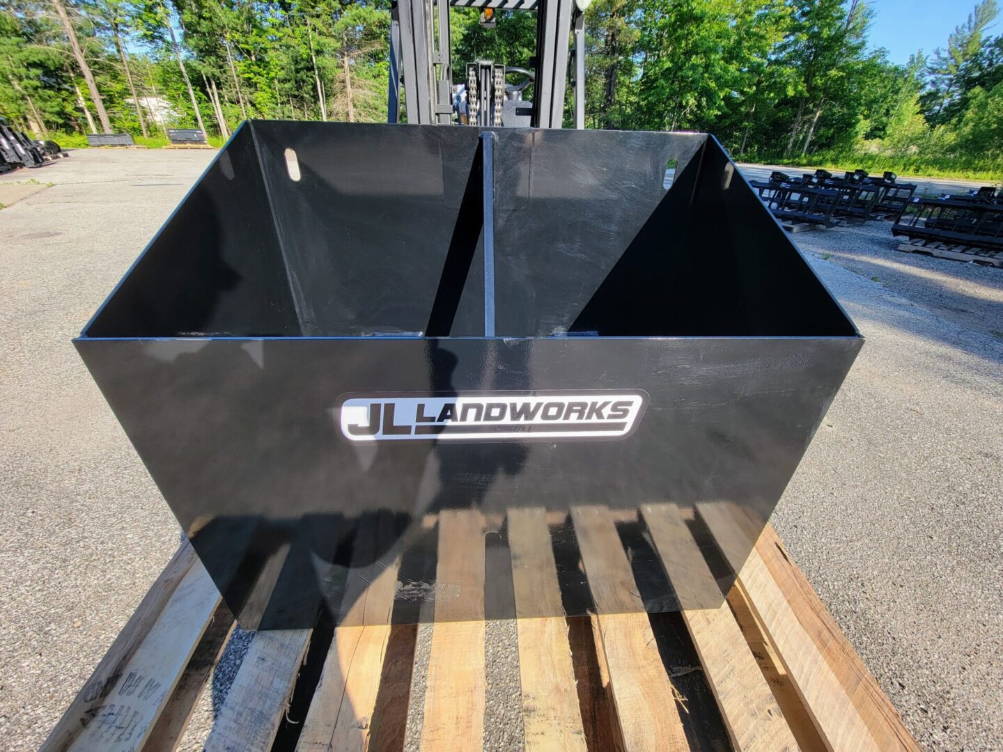 A black bin sitting on top of a wooden pallet.