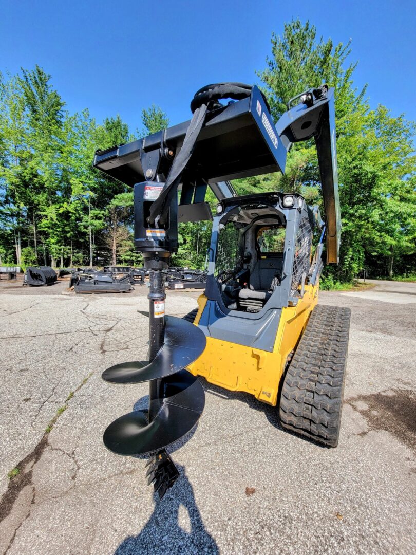 A yellow and black skid steer with a large attachment.