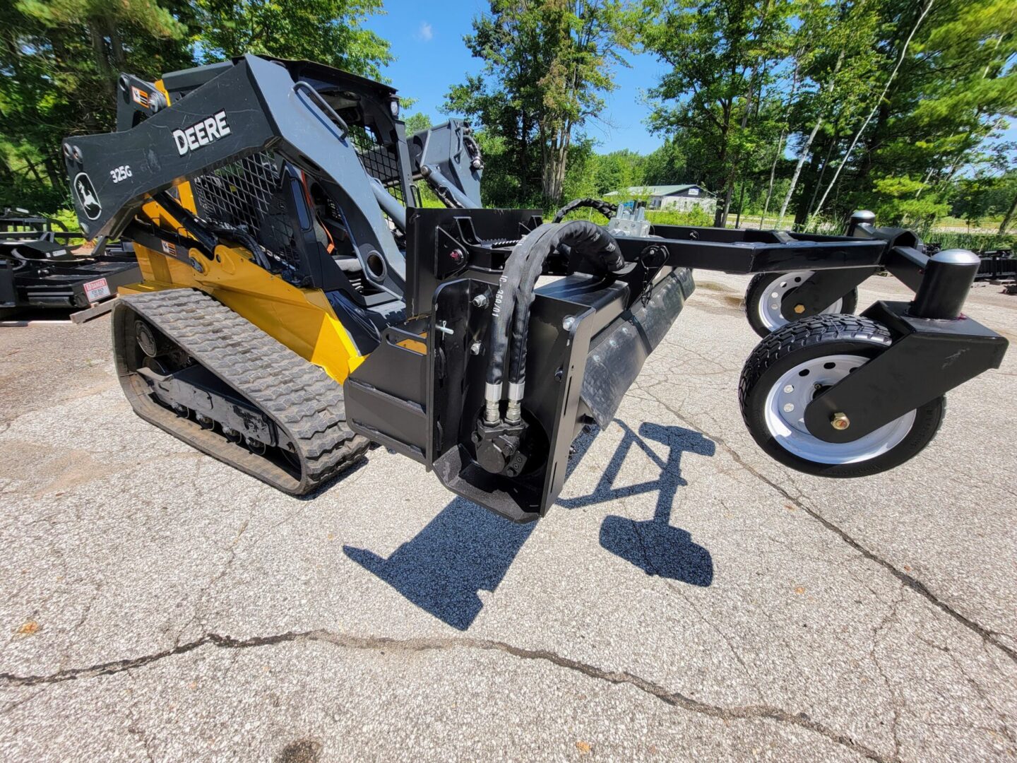 A black and yellow skid steer with a large attachment.