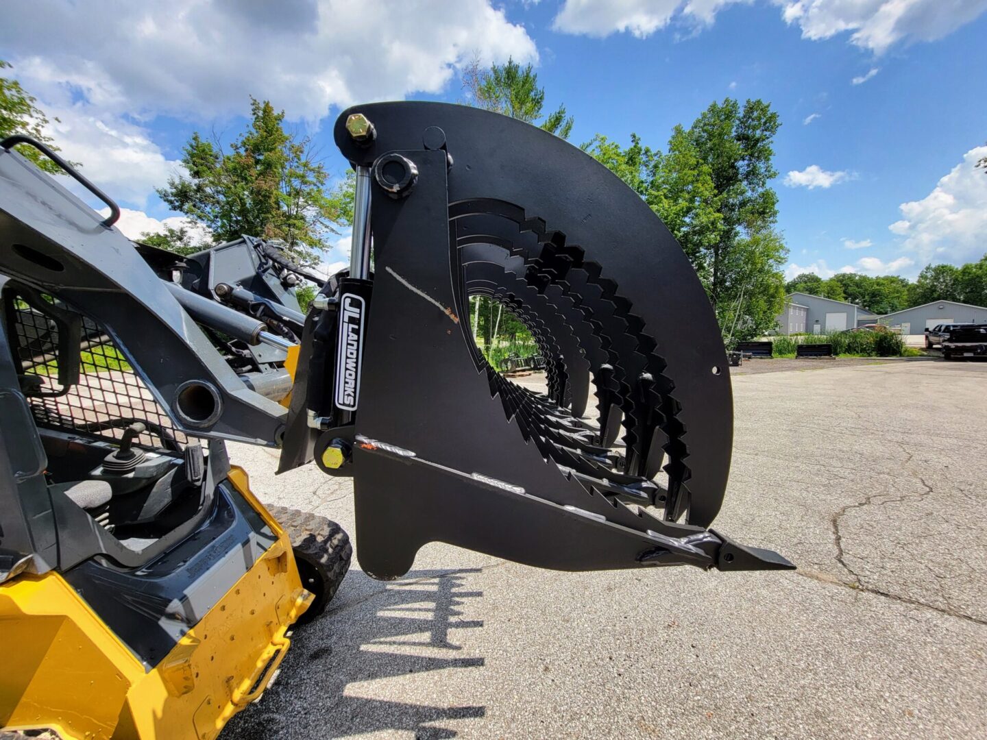 A large black metal wheel loader with trees in the background.