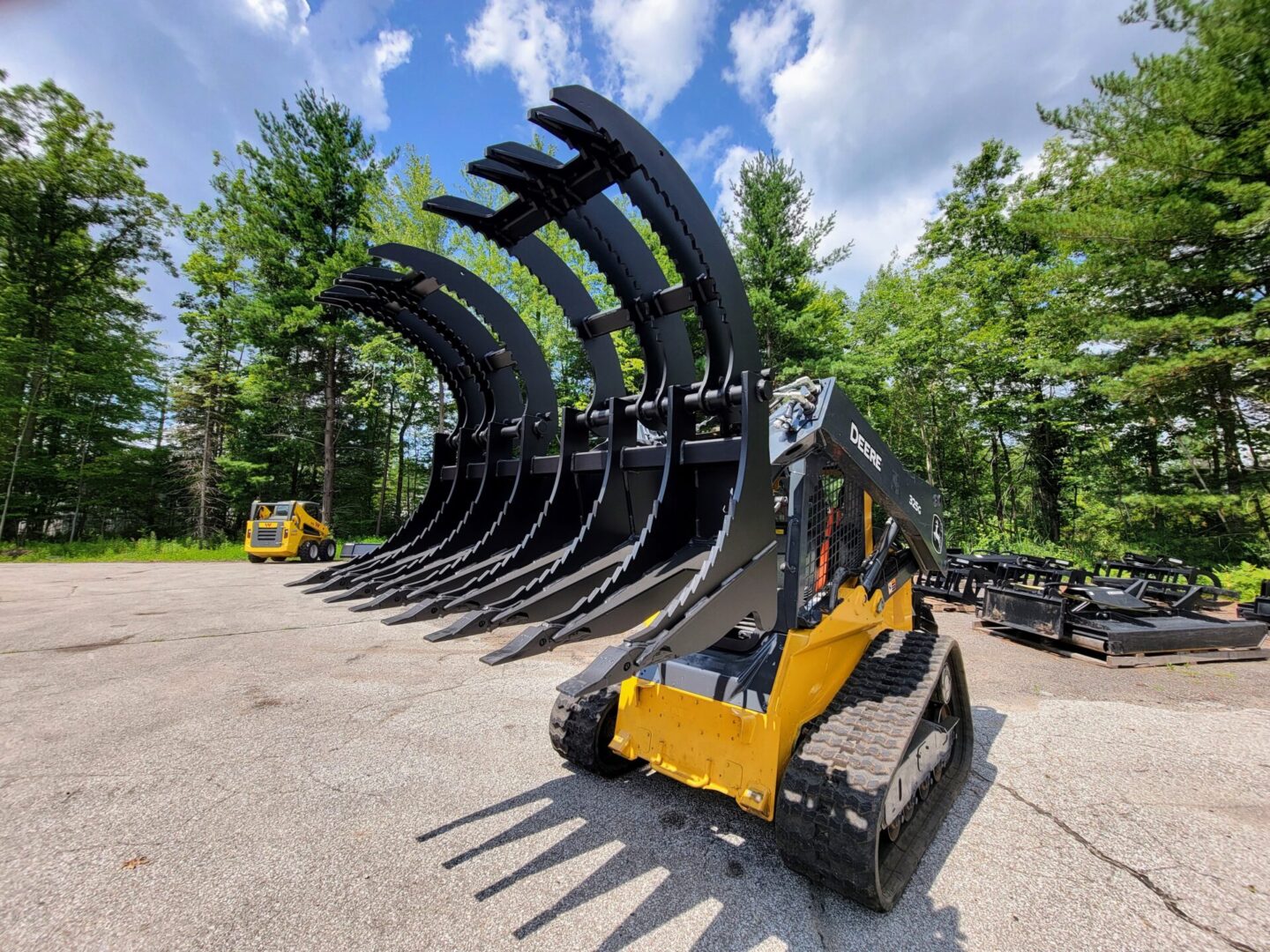 A yellow and black skid steer with many other equipment in the background.