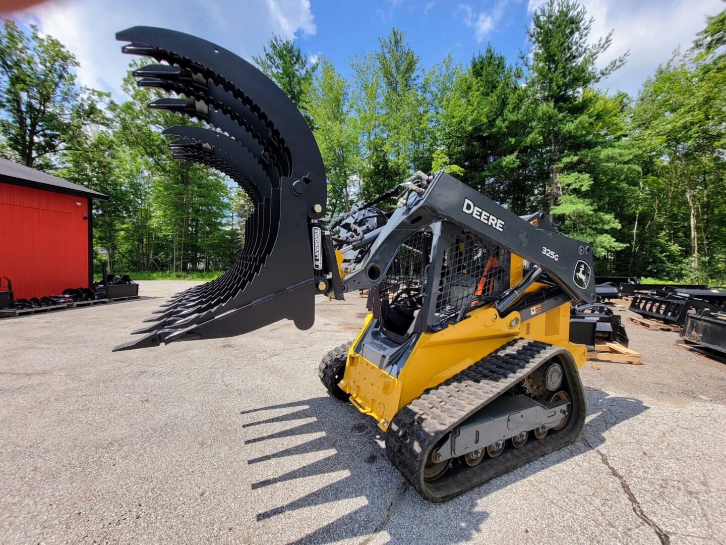 A yellow and black skid steer next to trees.