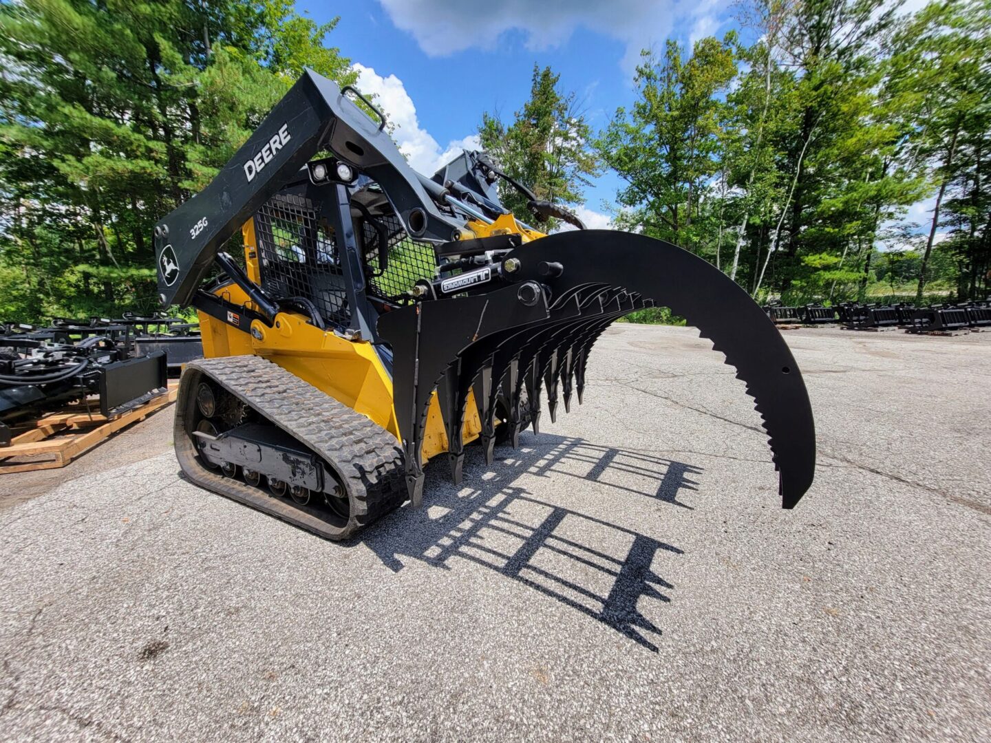 A yellow and black skid steer with a large claw attachment.