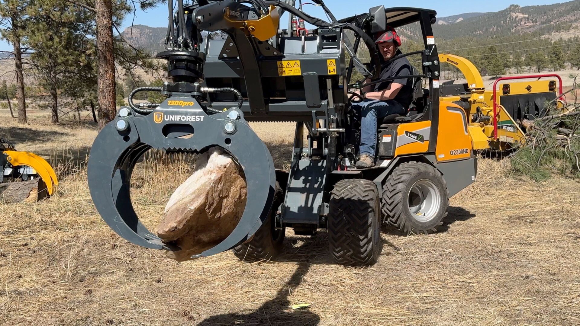 A man on the back of an orange and black tractor.