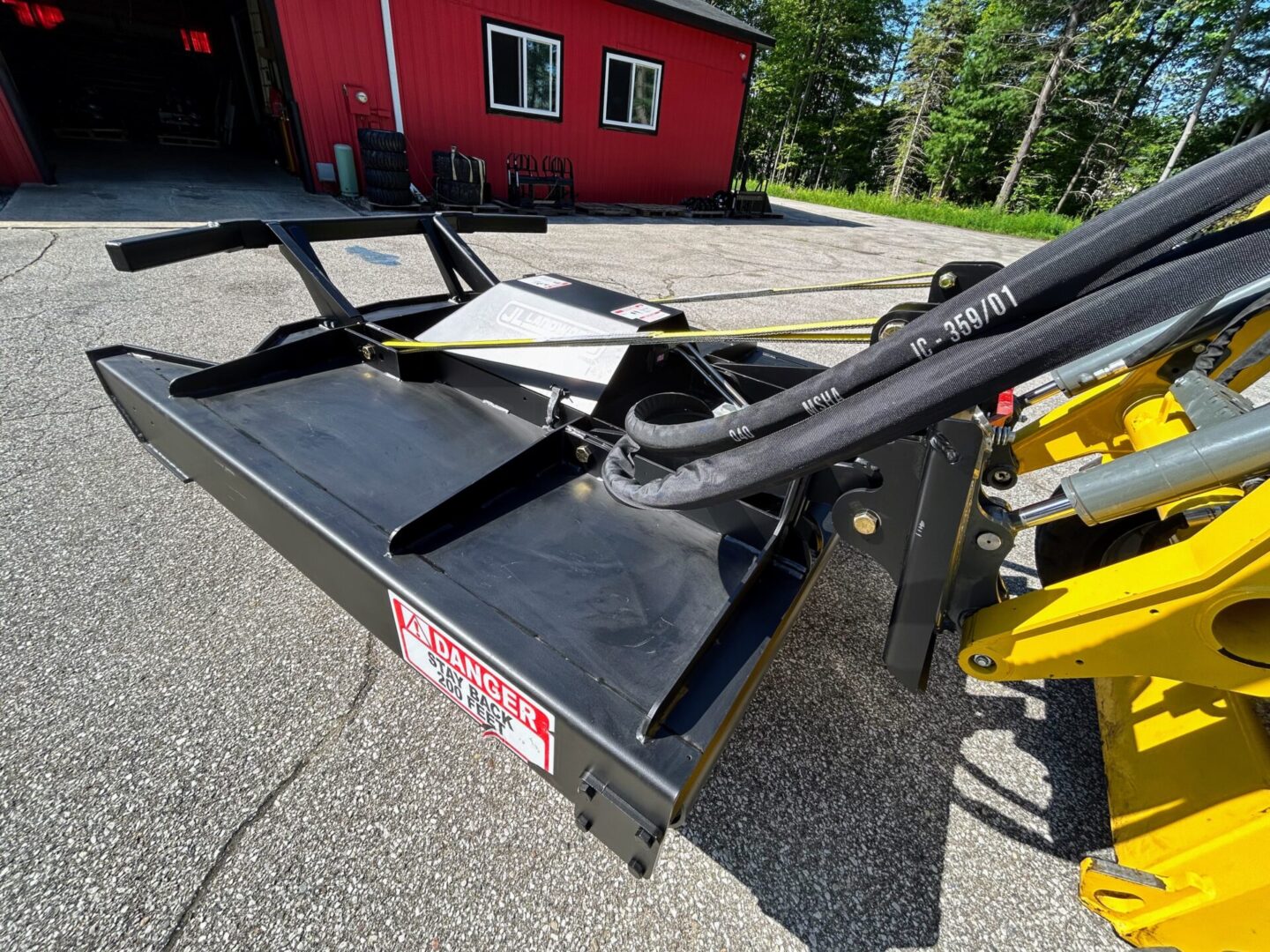 A black and yellow tractor with a red barn in the background.