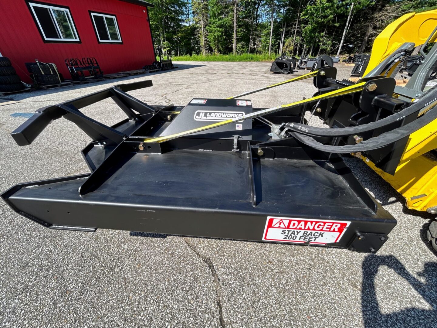 A black and yellow trailer with a red house in the background.