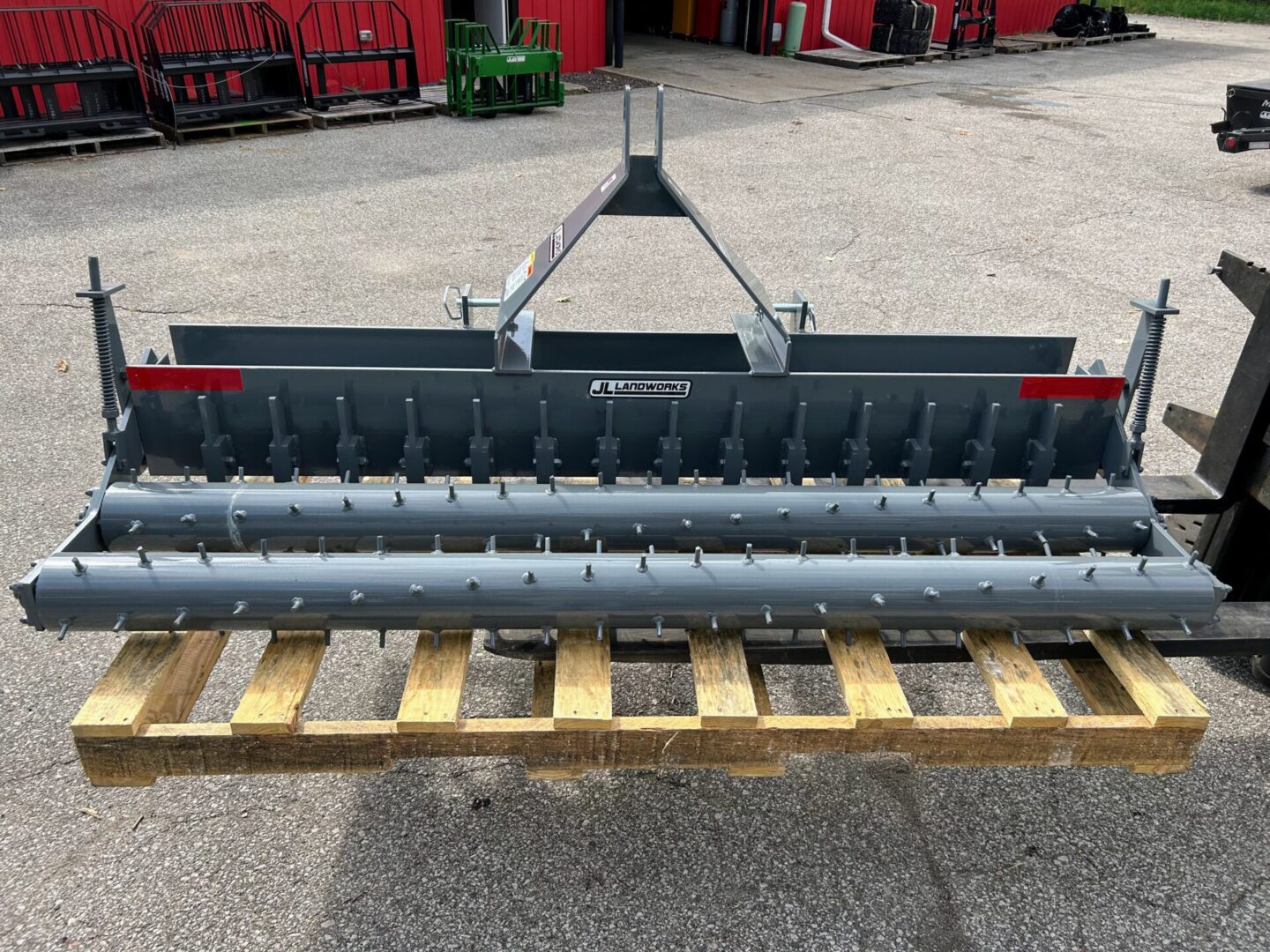 A large metal plow sitting on top of wooden pallets.