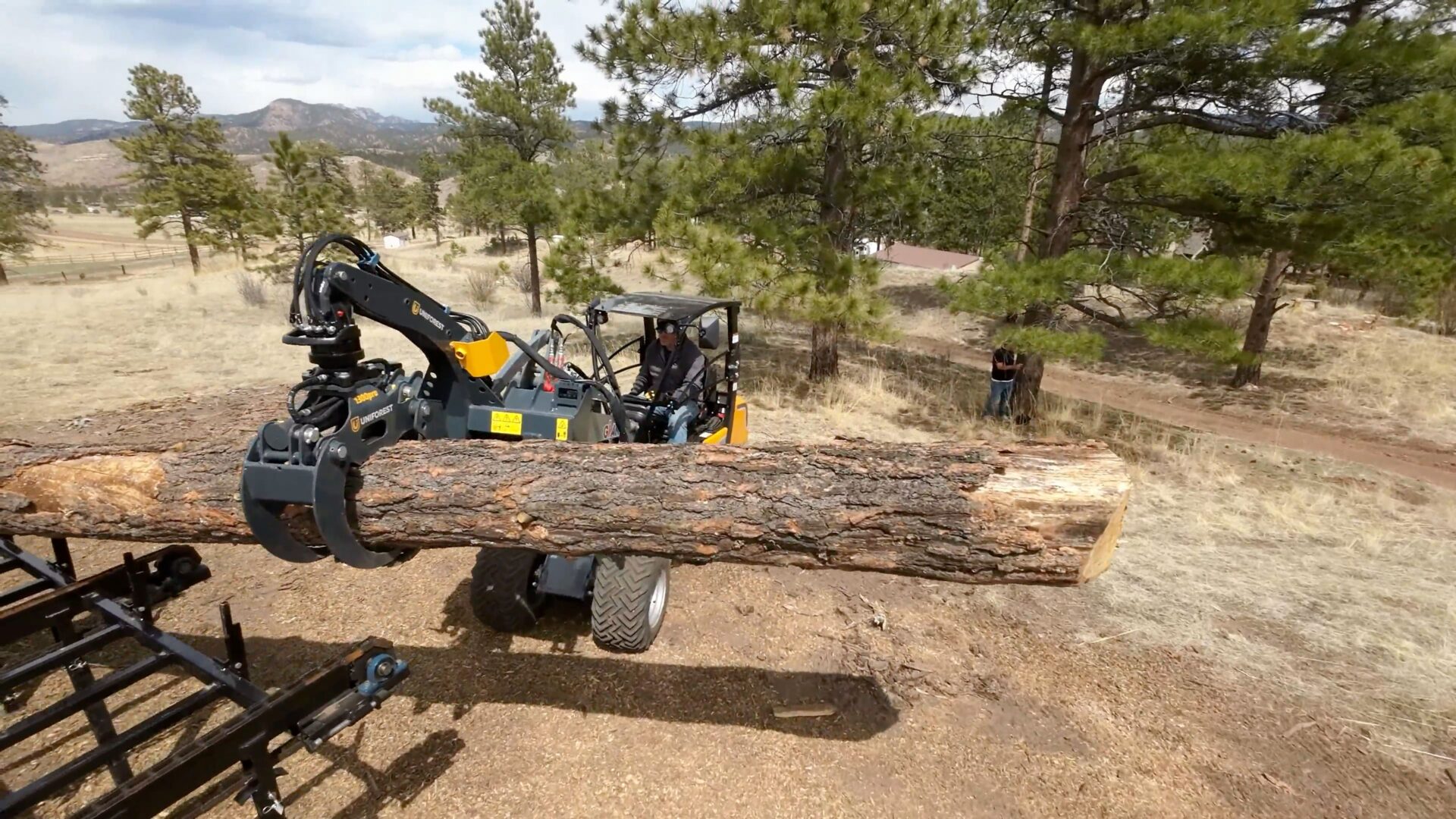 A large log being cut by a tractor.