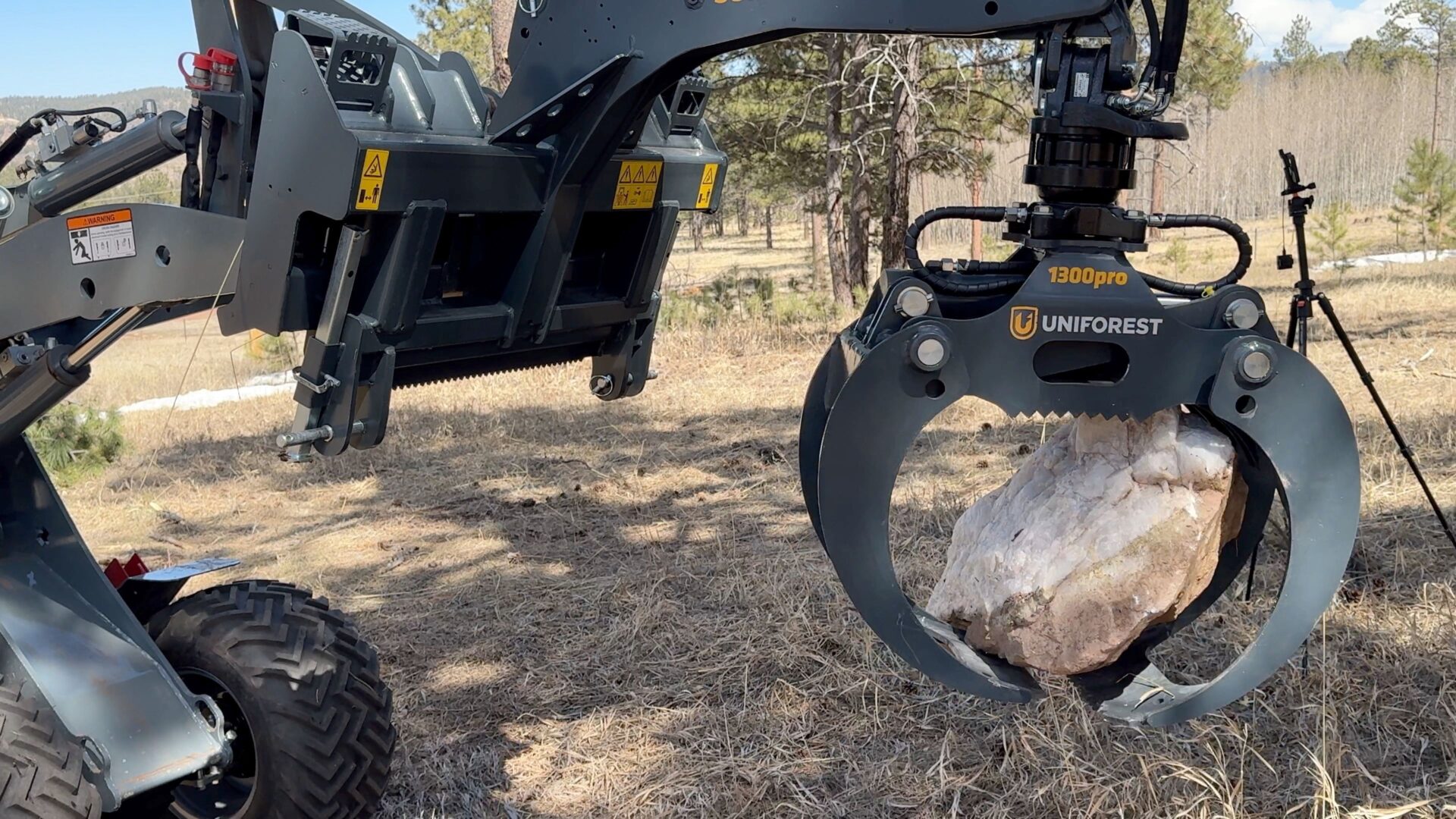 A large tree stump being held by a tractor.