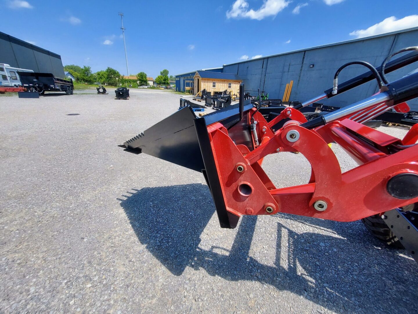 A red plow is parked in the middle of a parking lot.