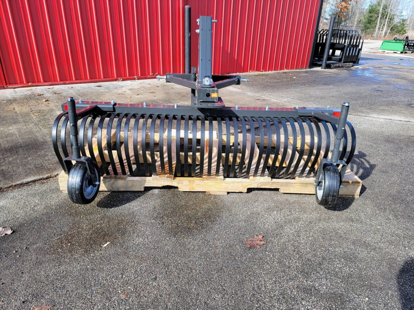 A large metal roller sitting on top of a wooden pallet.