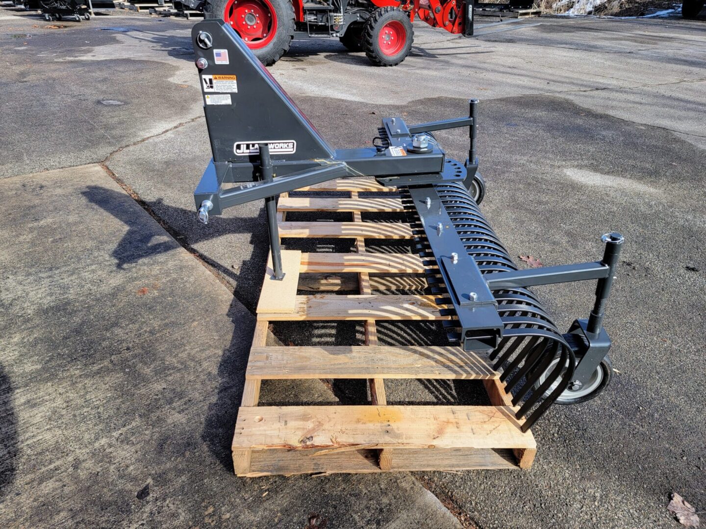 A pallet with a tractor mounted plow sitting on top of it.