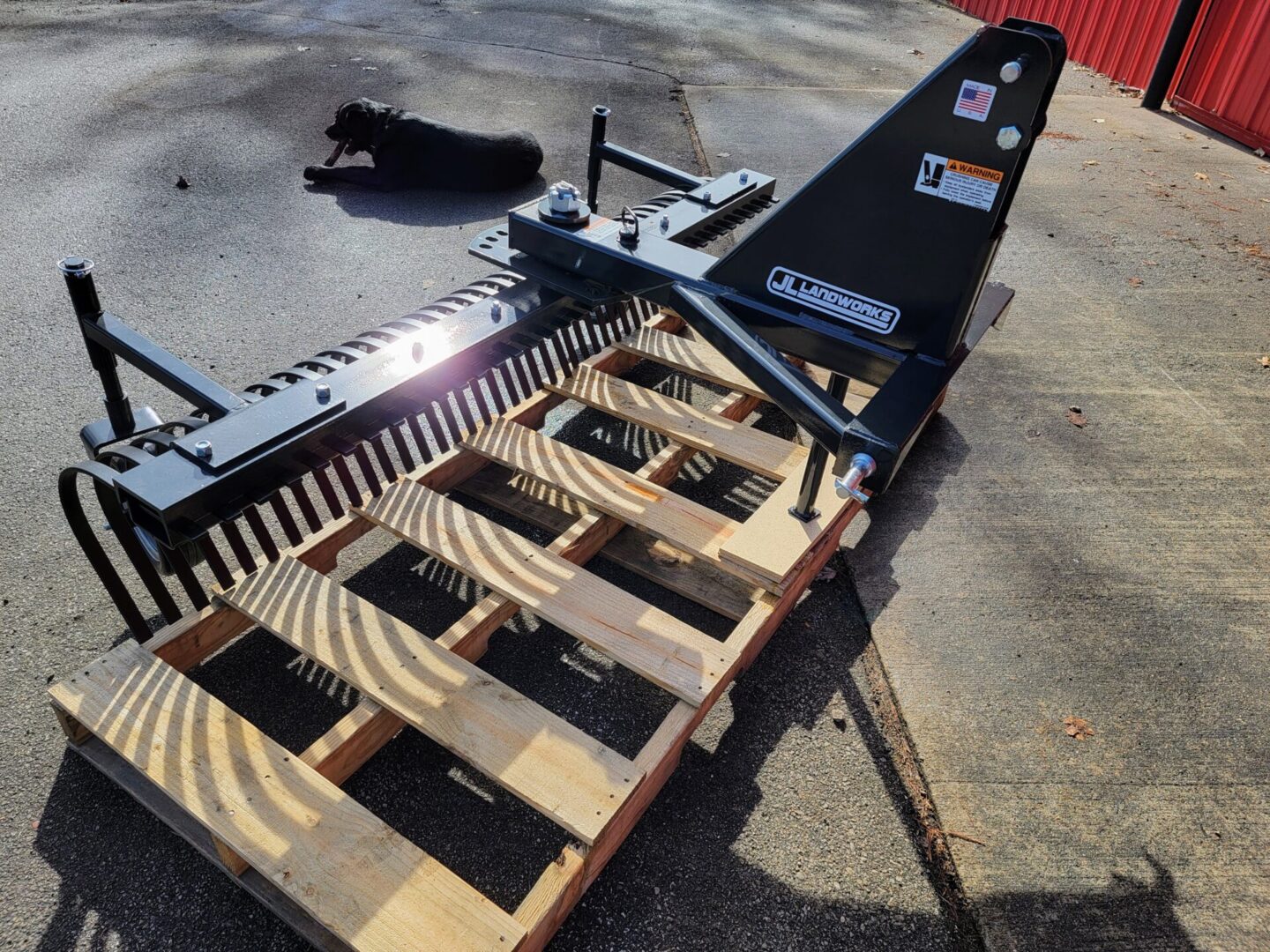 A black dog laying on top of a pallet.