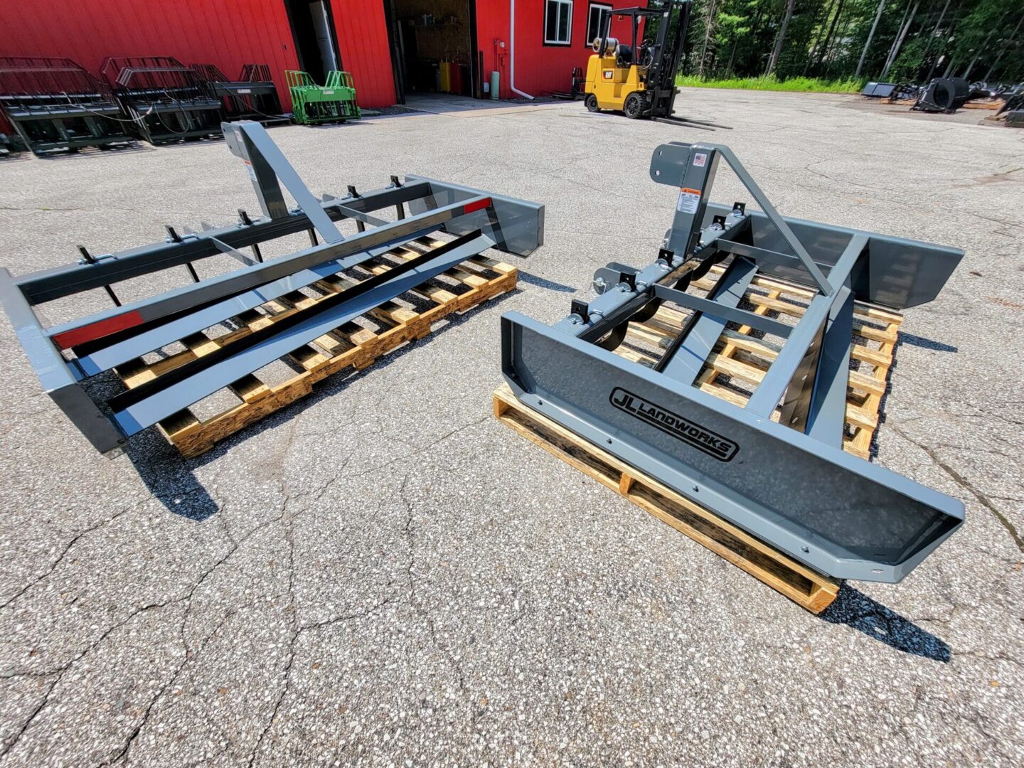 A pair of tractor attachments sitting on top of wooden pallets.